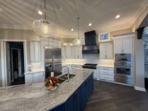 Modern kitchen with dark blue island cabinets, white painted cabinetry, granite countertop, and stainless steel appliances